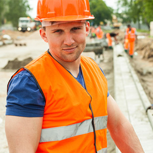 Seasonal worker in Florida wearing a hardhat and safety vest at a construction site